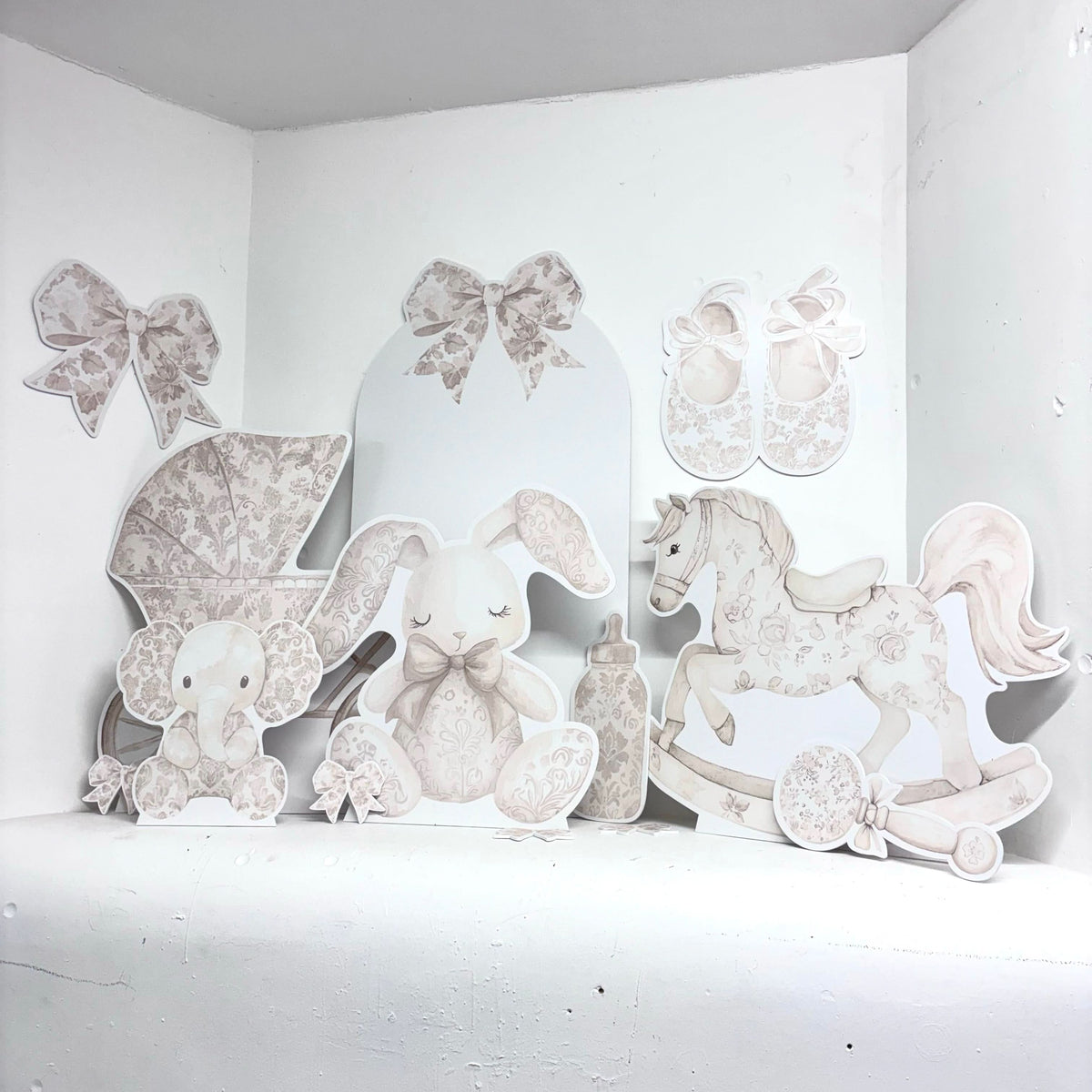 Neutral cream foamex baby props including rocking horse, stroller and bunny styled for a christening celebration