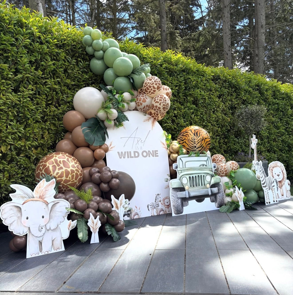 Safari themed first birthday display with shaped foamex backdrop, jeep and animal cutouts styled with a balloon garland