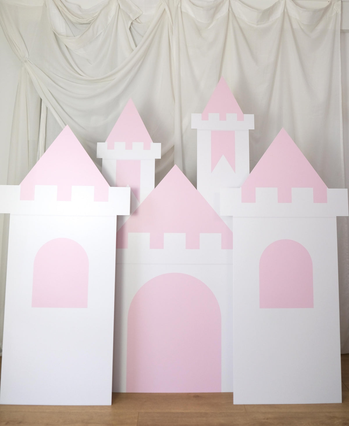 Angled view of Pink Princess Castle waterproof foamex castle set showing middle tower with battlements and two side towers with pink turrets and arched doorways princess party prop