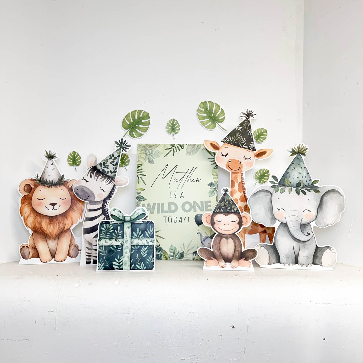 Mini First Birthday Wild One Bundle featuring personalised waterproof foamex safari animal cutouts including giraffe, zebra, and sign with jungle leaf decorations
