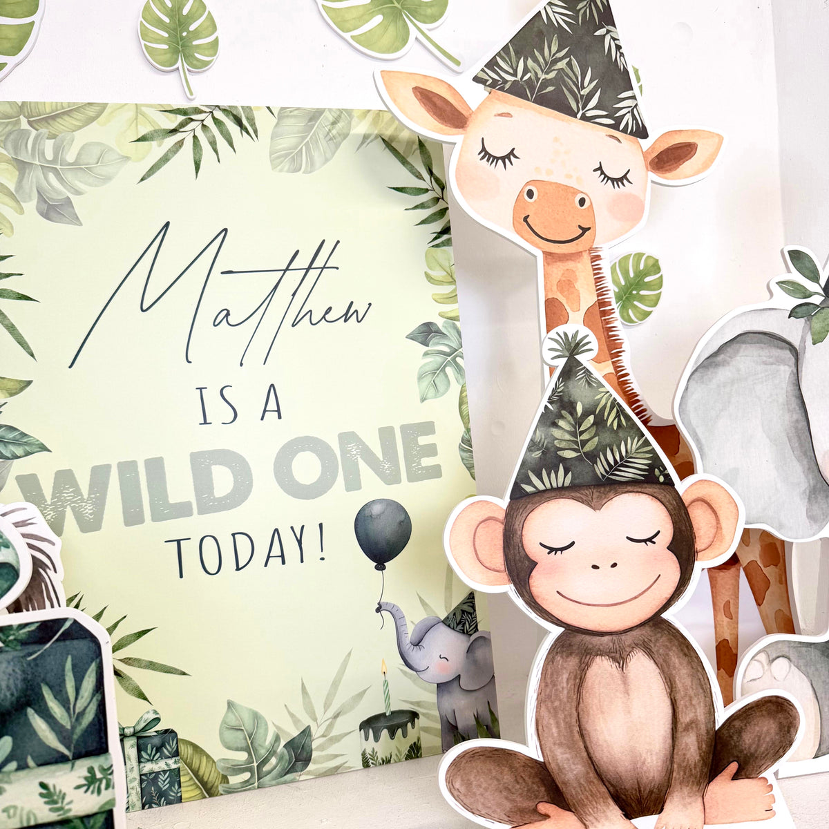 Close-up of Mini First Birthday Wild One waterproof foamex cutouts showing personalised sign, giraffe, monkey, and safari animals with jungle leaf decorations