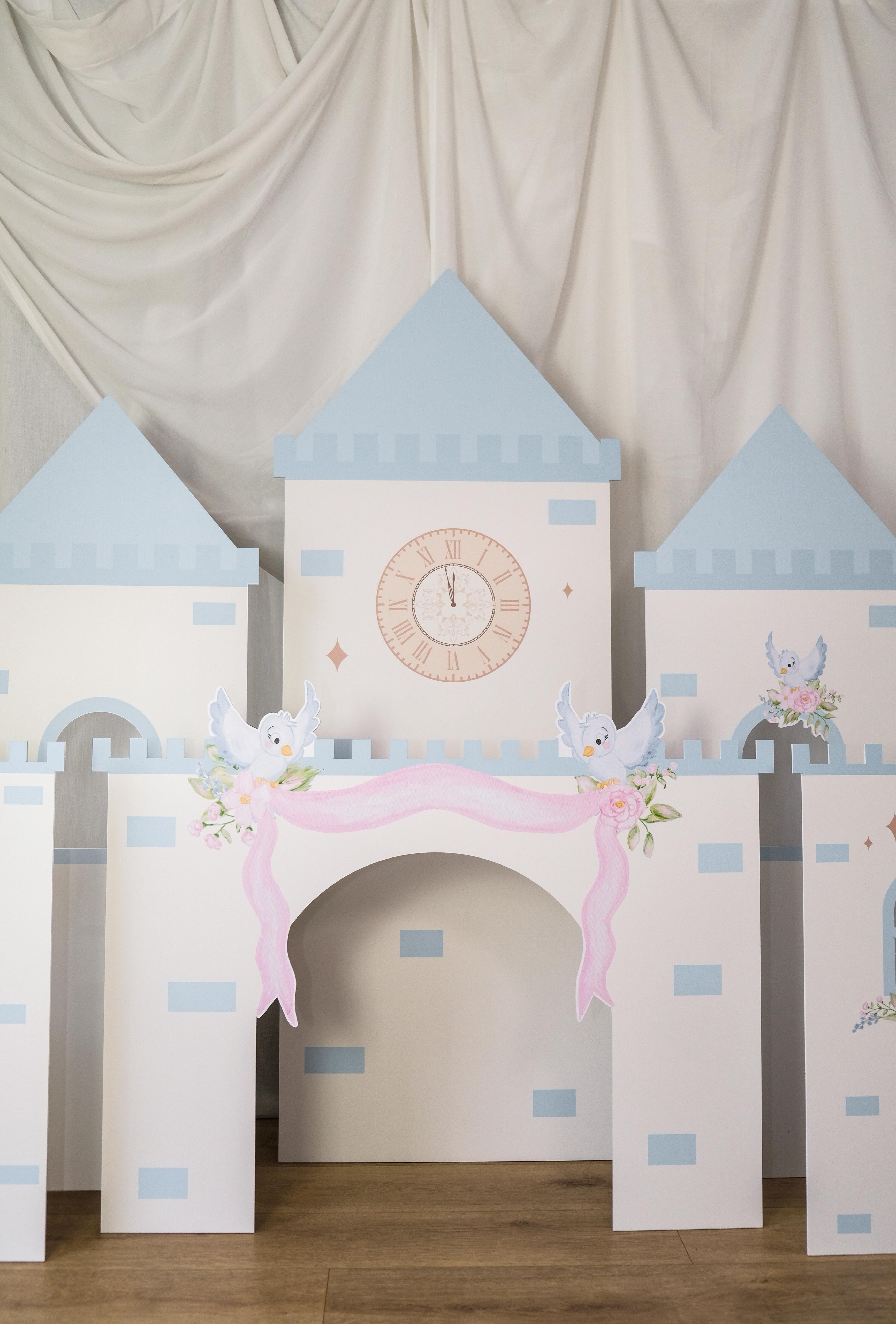 Full view of Midnight Castle waterproof foamex castle set showing all five towers with blue turrets, clock face, arched doorway with pink drapes and rose decorations party prop