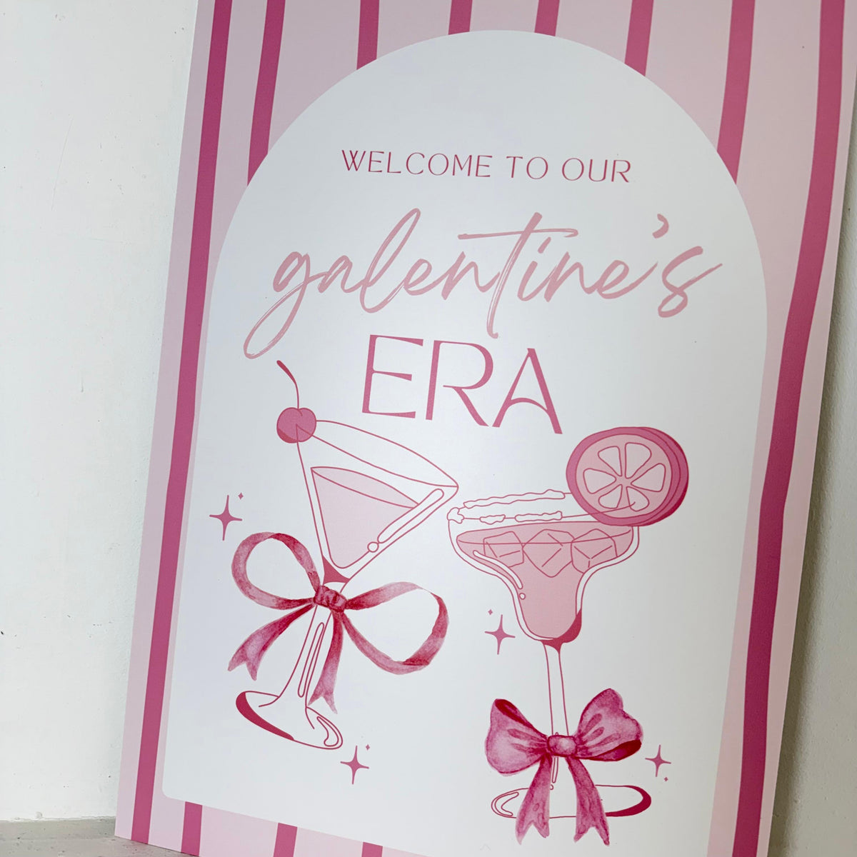 Personalised Galentines Era party easel sign close-up with Welcome to Our Galentine's Era text, cocktails, and pink bows - waterproof foamex by Zebra Print Events