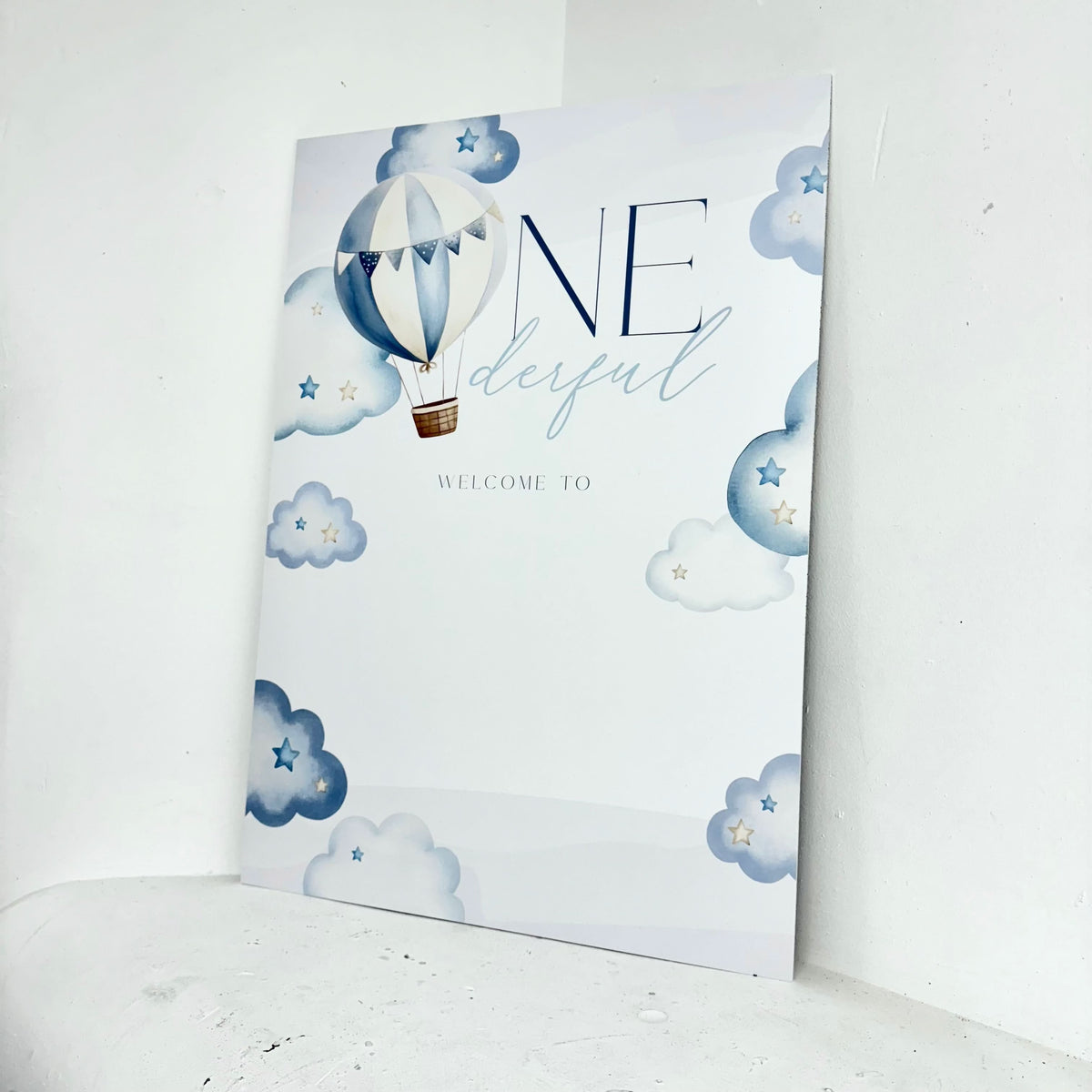 Close-up of One-derful personalised first birthday welcome sign with hot air balloon, clouds and stars design on freestanding foamex board