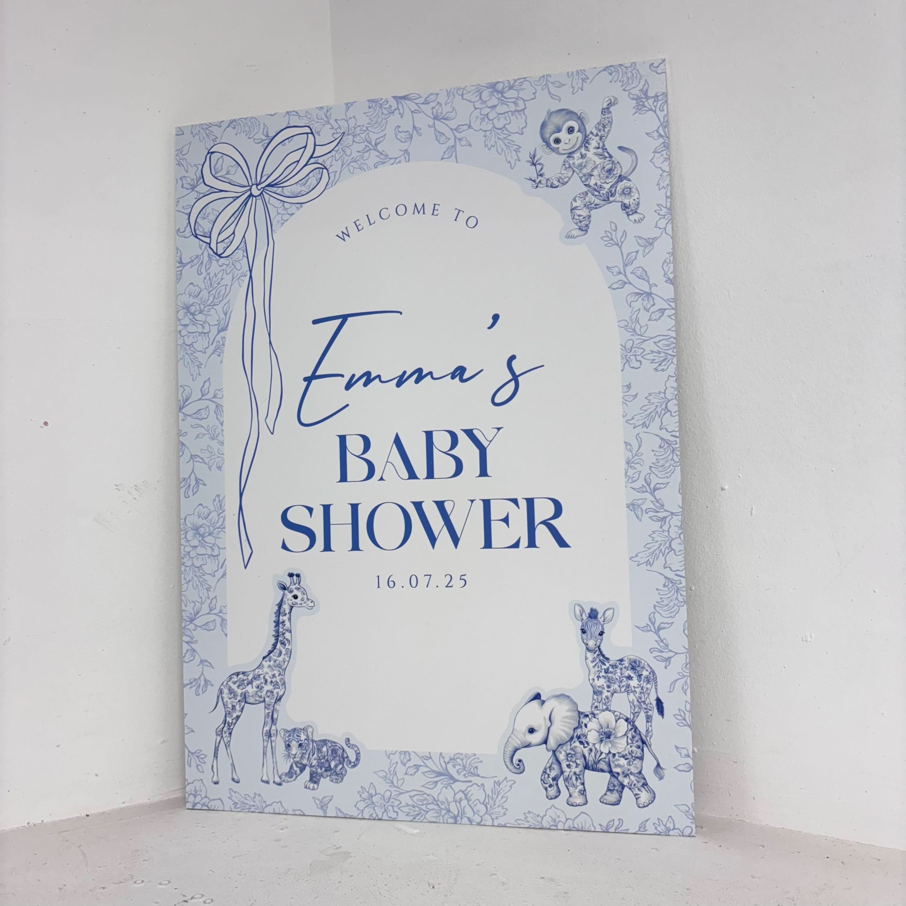 Angled view of Toile Safari personalised baby shower welcome sign on waterproof foamex board featuring blue toile-style safari animals and floral border design