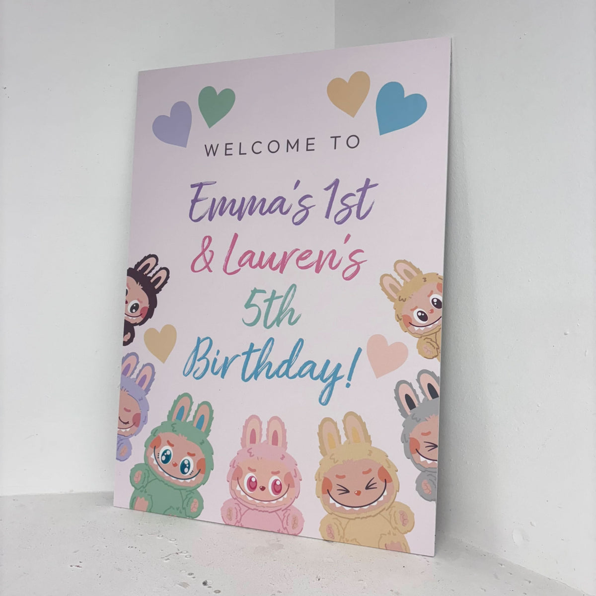 Little Monsters easel sign angled view showing personalised names and ages with colourful monster illustrations on freestanding foamex board