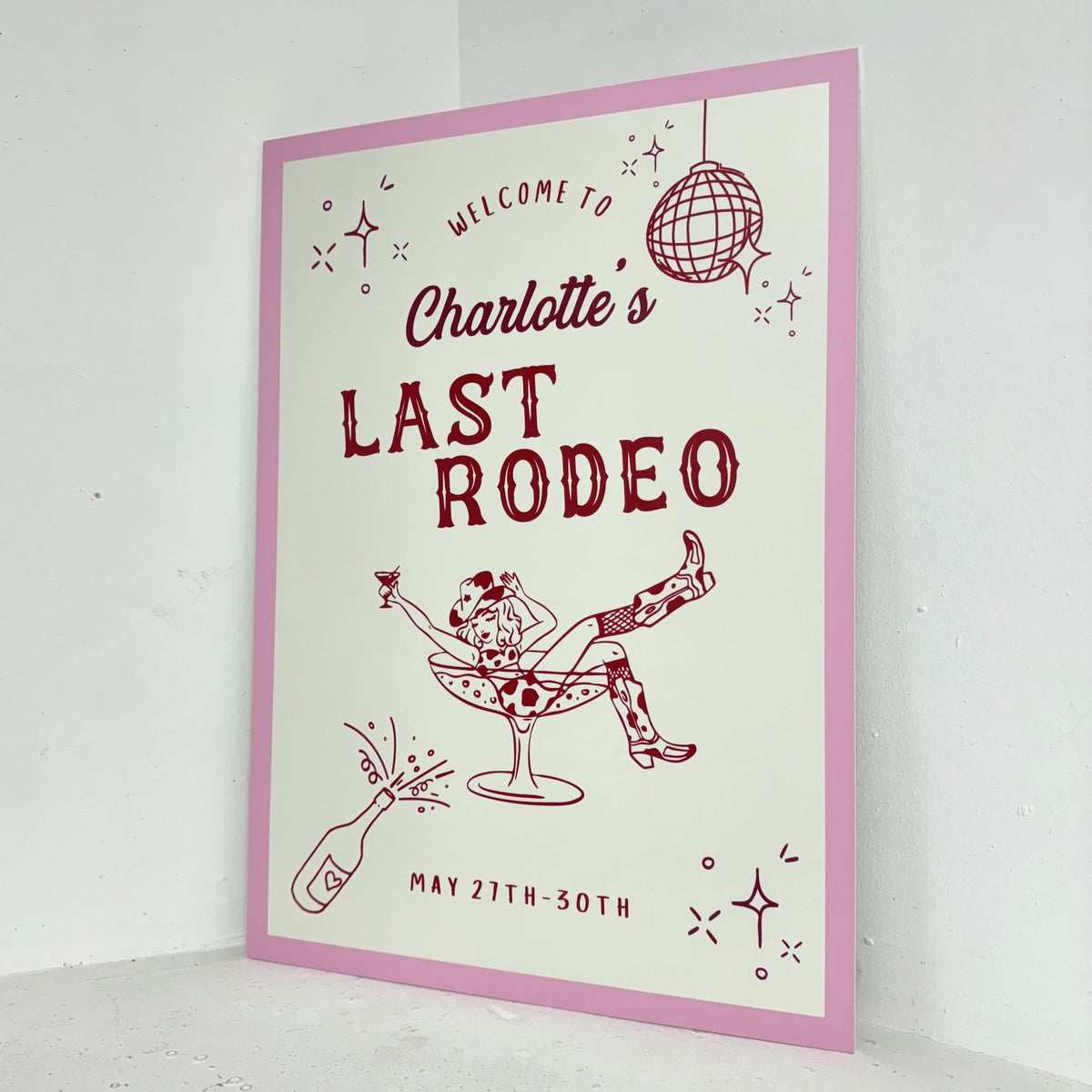 Angled view of Last Rodeo personalised hen party welcome sign on waterproof foamex board with pink border, cowgirl illustrations, and retro western design