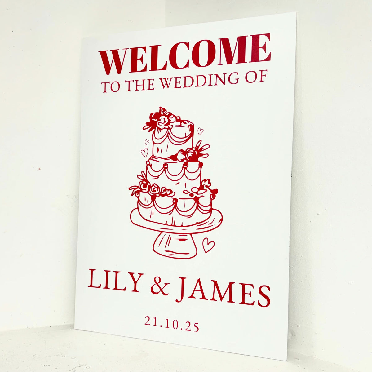 Angled view of Red and White Wedding personalised welcome sign on waterproof foamex board with bold red typography and decorative wedding cake design