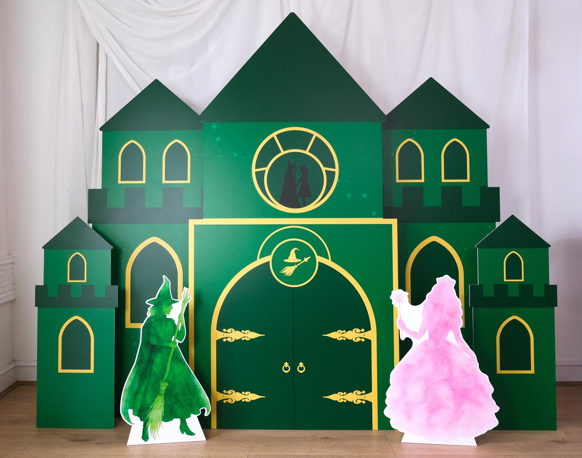 Emerald Castle cutout backdrop with green towers, gold decorative details and character figures – enchanted party prop by Zebra Print Events