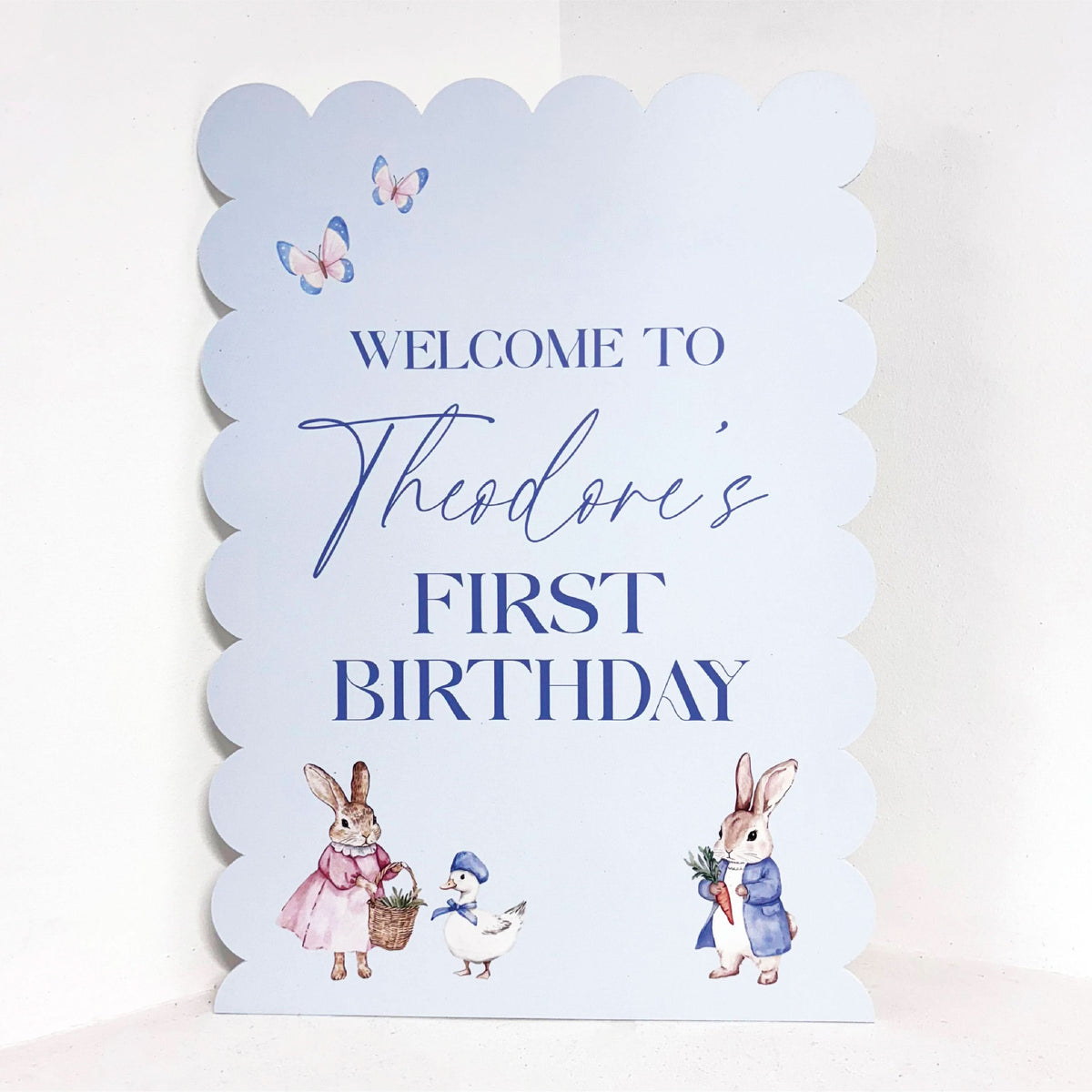 Cottontail Spring personalised 1st birthday easel sign with rabbit illustrations, butterflies and custom name on blue waterproof foamex board