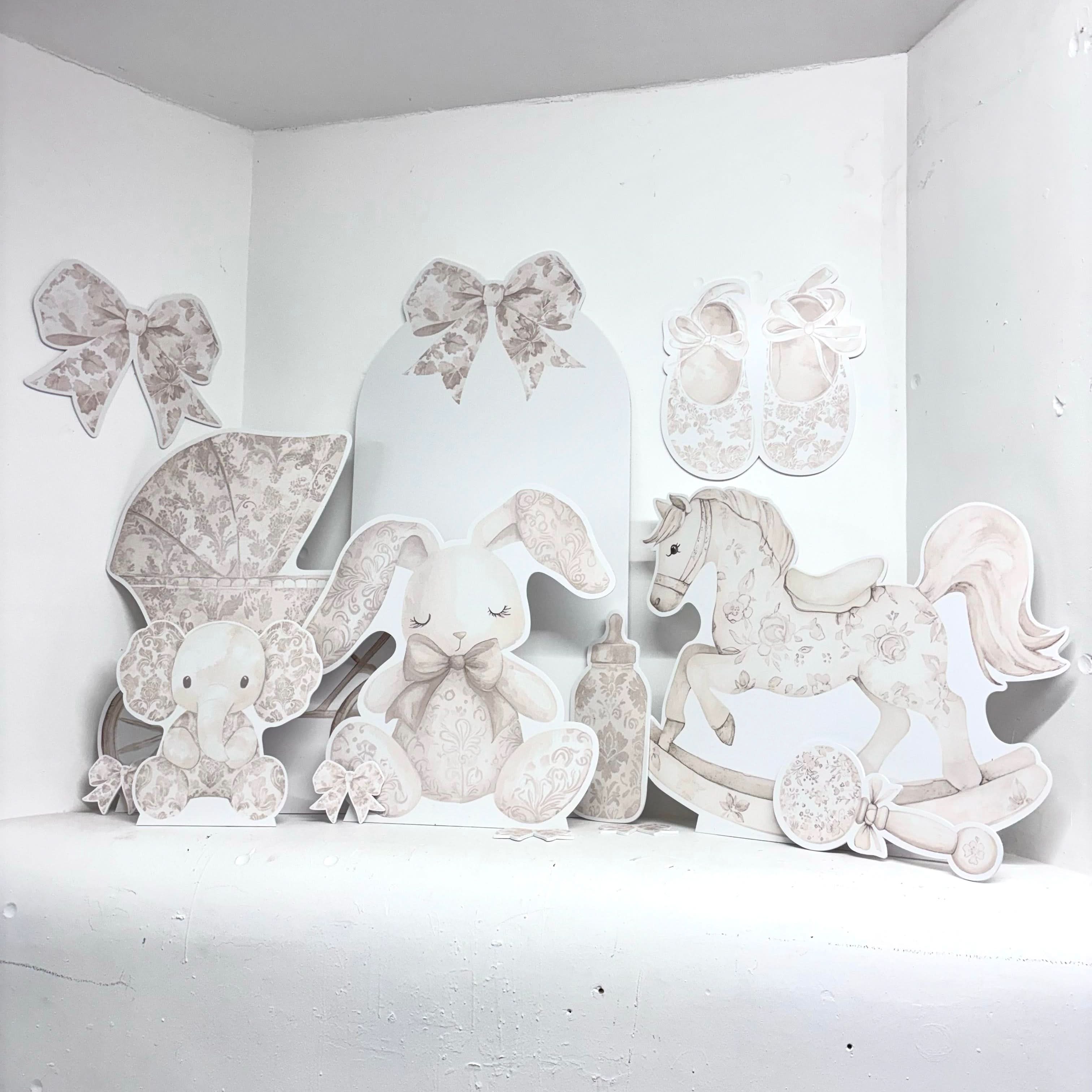 Neutral gender reveal styling with cream foamex baby props including rocking horse, stroller and bunny cutouts