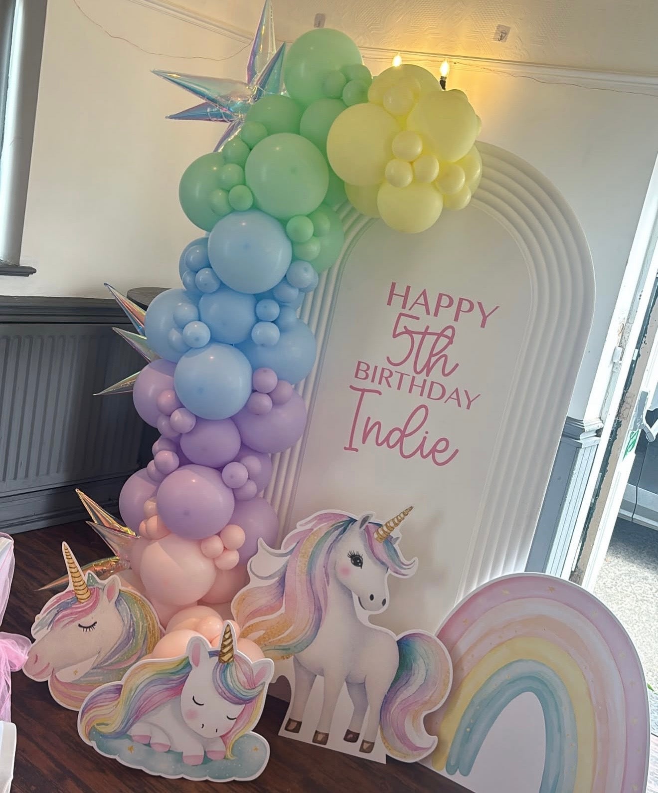 Personalised pastel unicorn 5th birthday backdrop with arch board, unicorn cutouts and rainbow balloon garland