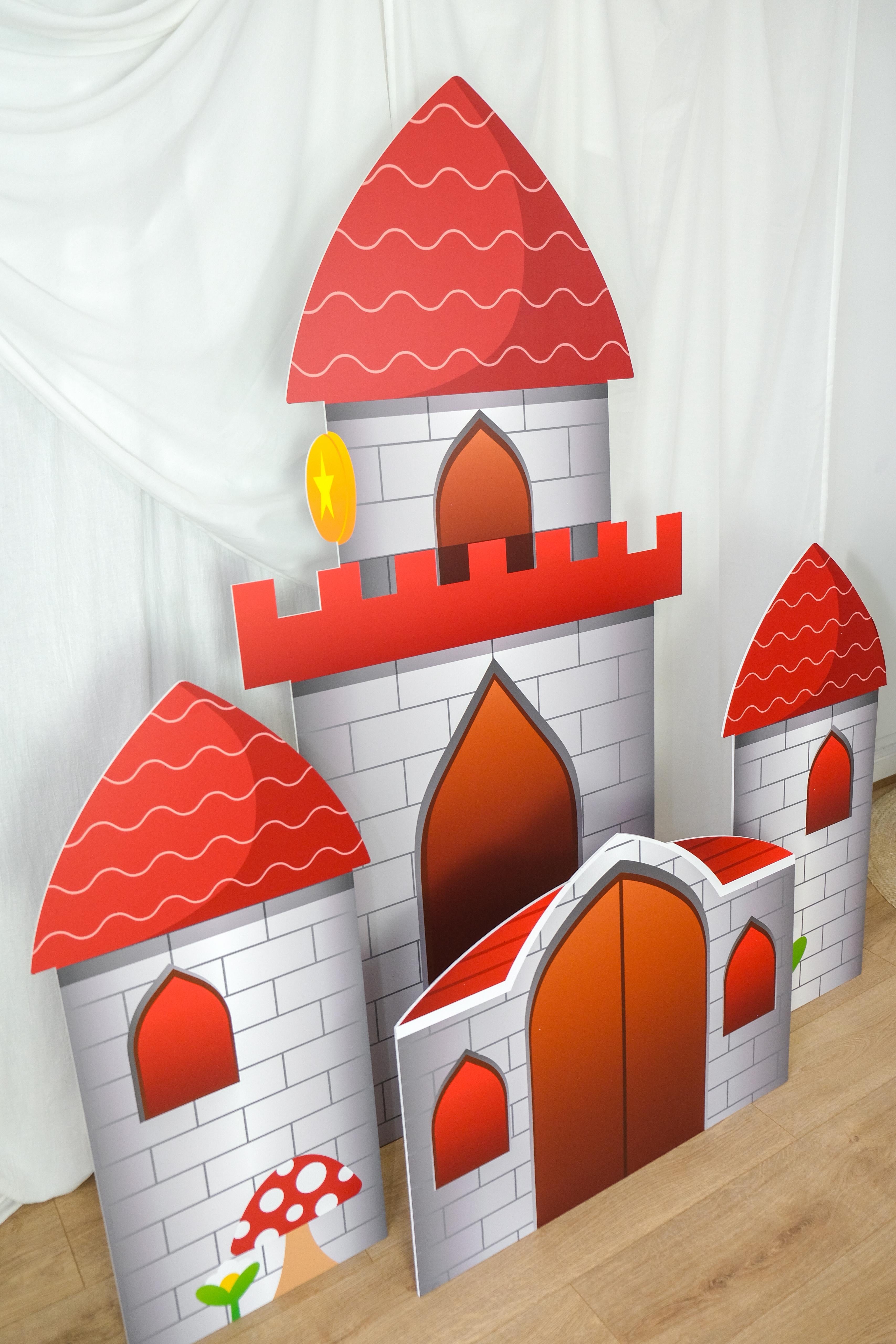 Front view of Gaming Castle waterproof foamex castle set showing all towers with red roofs, stone-effect walls, battlements, and mushroom detail gaming party prop