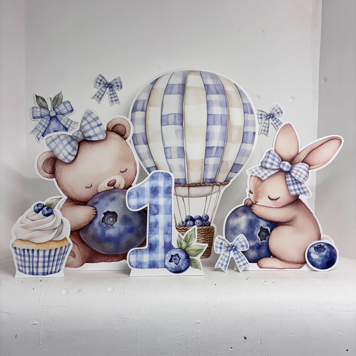 Close-up of Mini Blue Berry First Birthday waterproof foamex cutouts showing teddy bear, hot air balloon, bunny, and number one with blueberry accents