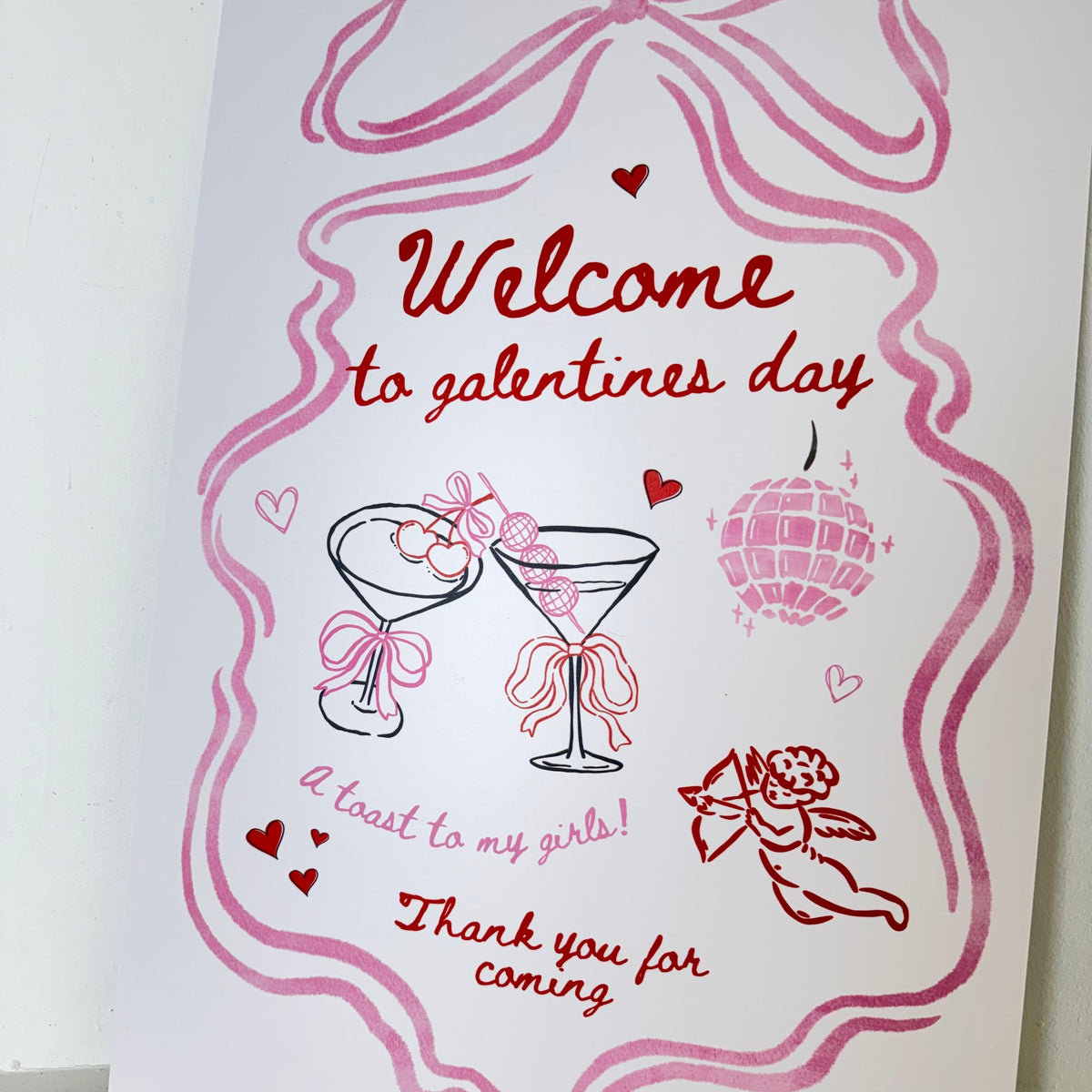 Personalised A Toast To My Girls easel sign close-up with pink ribbons, hearts, cocktails, and cherub - waterproof foamex Galentine's Day welcome sign by Zebra Print Events