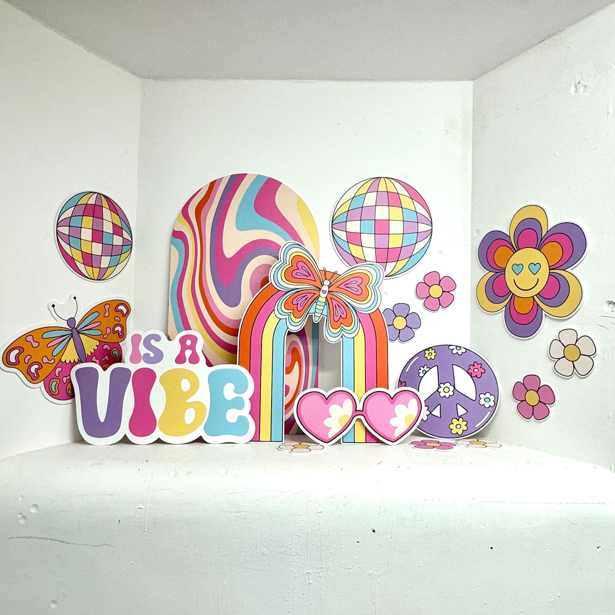 What a Vibe Bundle featuring personalised waterproof foamex cutouts including retro swirl sailboard, butterfly sailboard, Is a Vibe sign, disco balls, smiley flowers, heart sunglasses, and peace sign party decorations