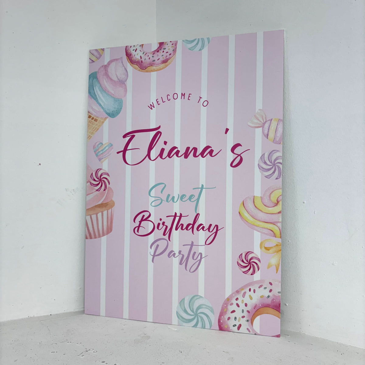 Sweet Birthday easel sign angled view showing personalised name with colourful candy illustrations on freestanding foamex board