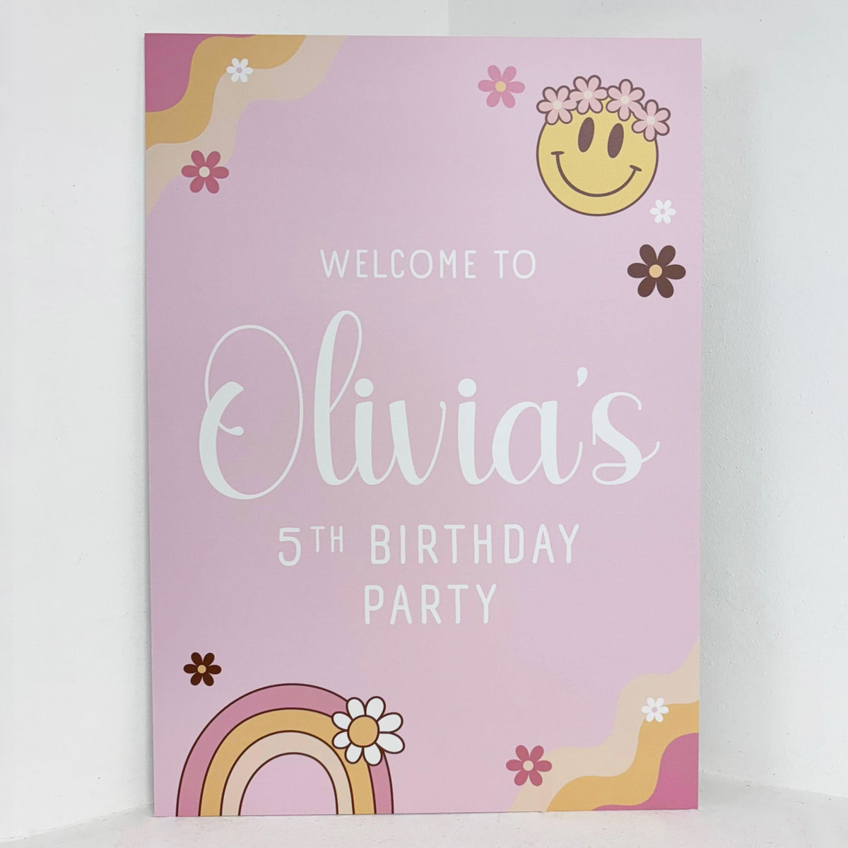 Pink Groovy personalised birthday easel sign with retro smiley face, rainbow and flower design, featuring welcome text, custom name and age on waterproof foamex board