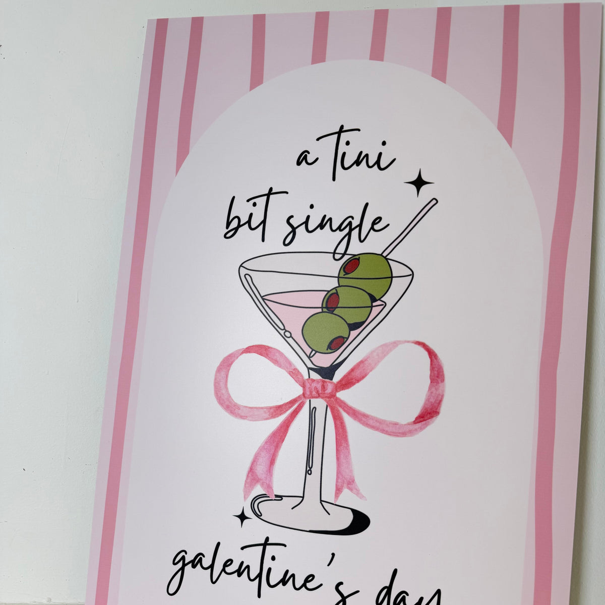 Close-up angled view of Tini Bit Single Galentine's Day foamex easel sign with martini glass and pink bow design