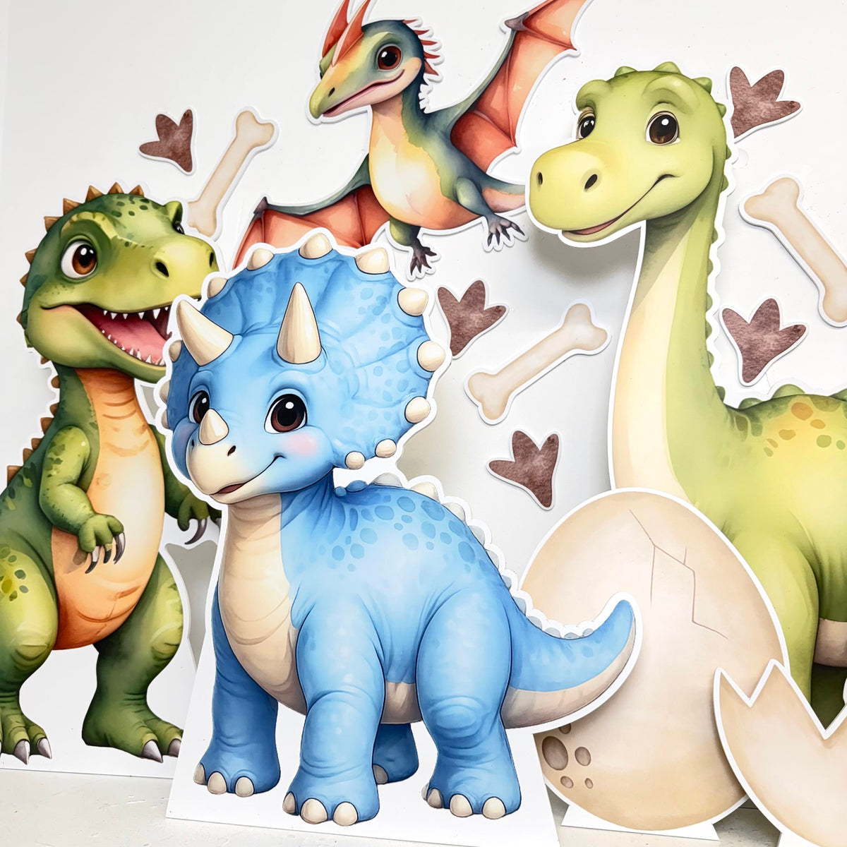 Dinoland mini cutout bundle featuring colourful cartoon dinosaur props including green dino, T-Rex and blue dino with stands, perfect for dinosaur themed party decorations