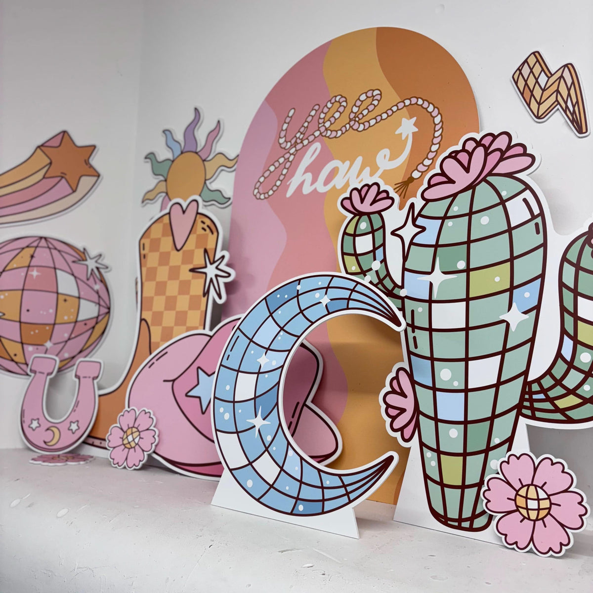 Close-up of Disco Rodeo Bundle waterproof foamex cutouts showing retro cactus, disco ball moon, yee haw sailboard, cowboy boot, stars, flowers, and lightning bolt party decorations